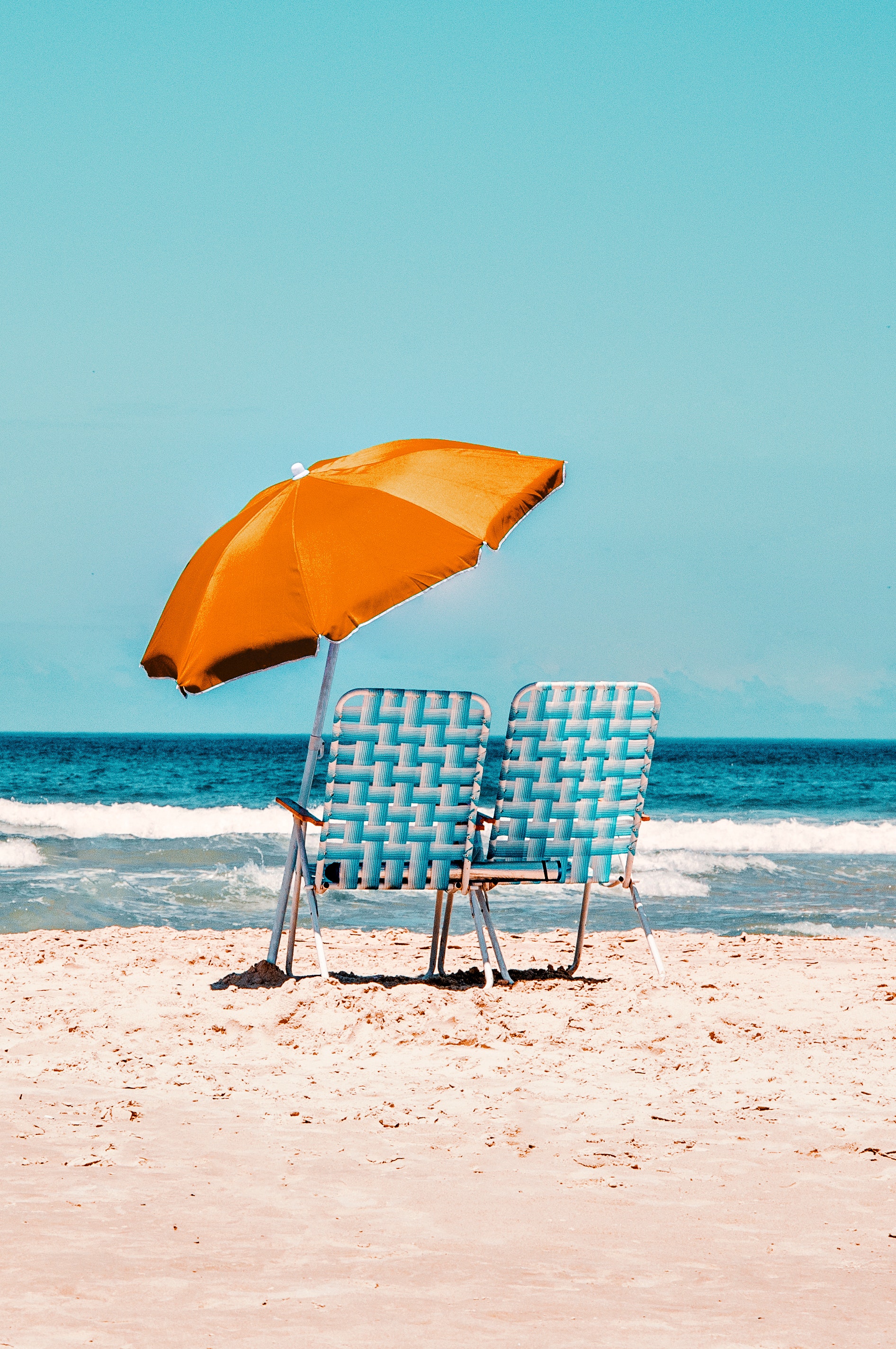 Twee strandstoelen met een parasol. In het zand geplaatst, gericht op de zee