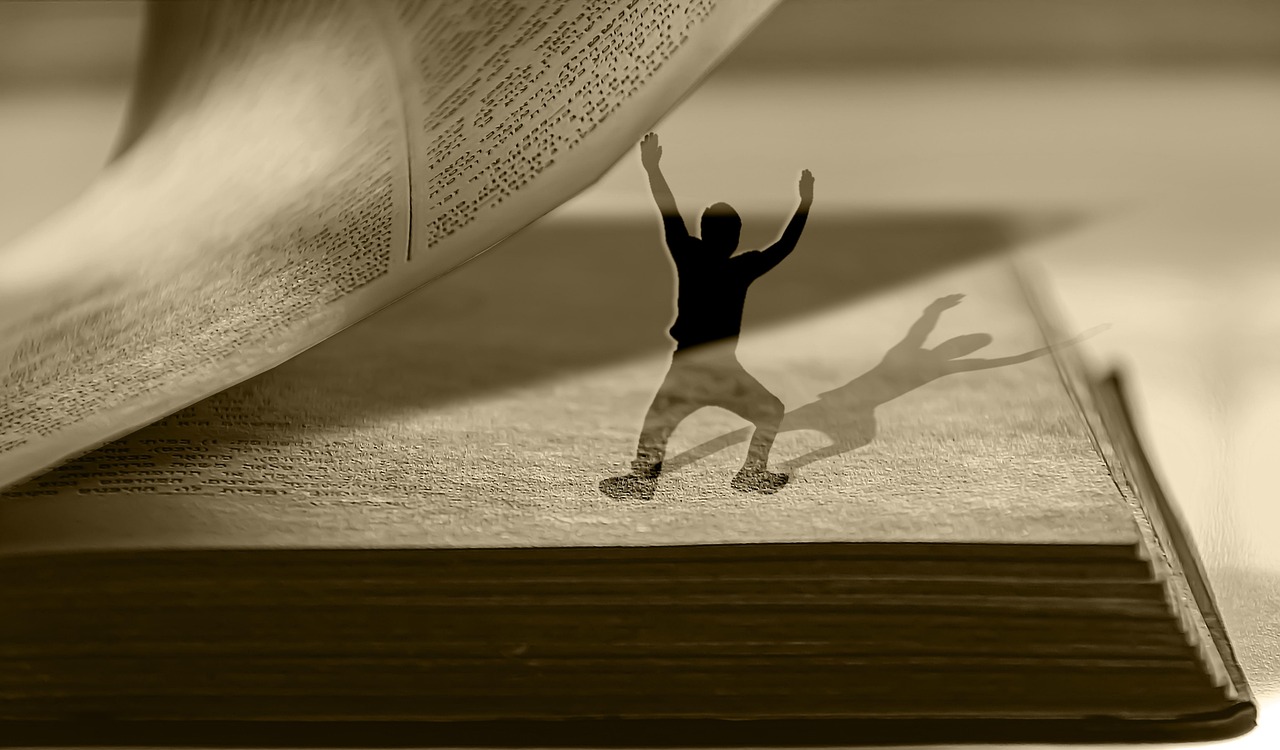 Silhouet van een man houdt de pagina van een openliggend boek omhoog met zijn handen