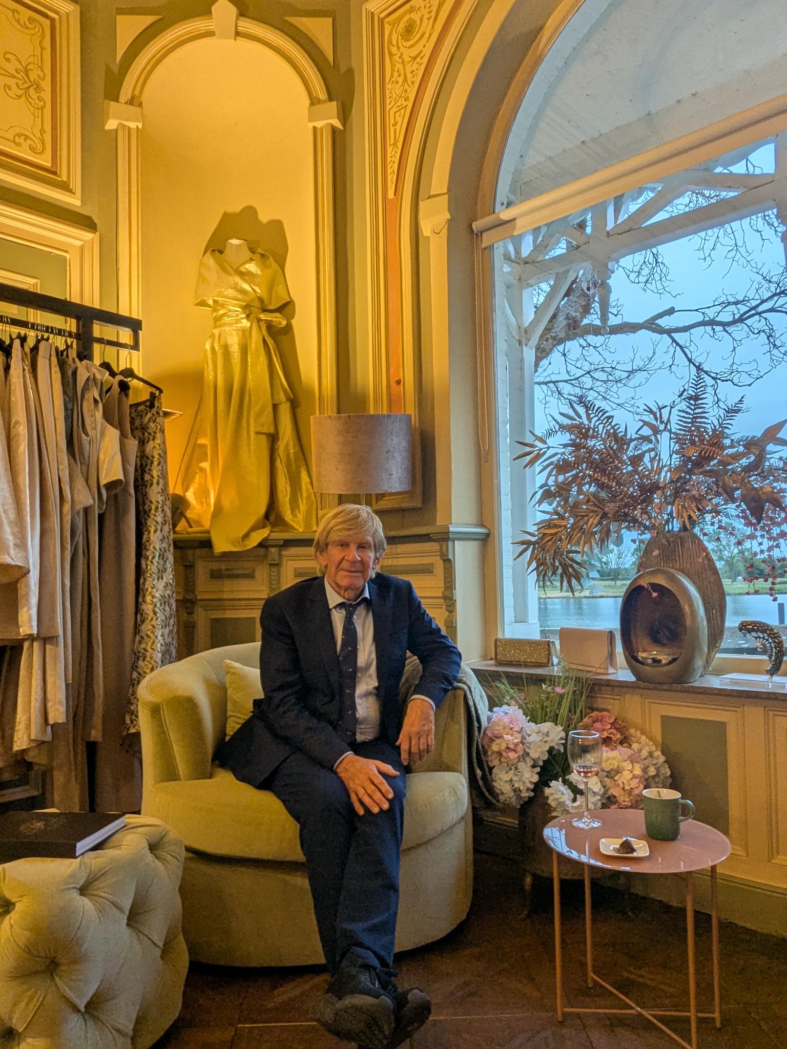 Addy van den Krommenacker, zittend in een luxe stoel in een rijk gedecoreerde ruimte