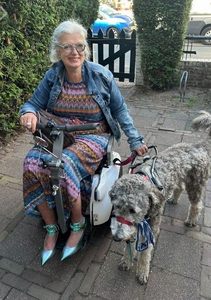 Lidwien Cornelissens, buiten in haar scootmobiel, met naast haar haar geleidehond Sam