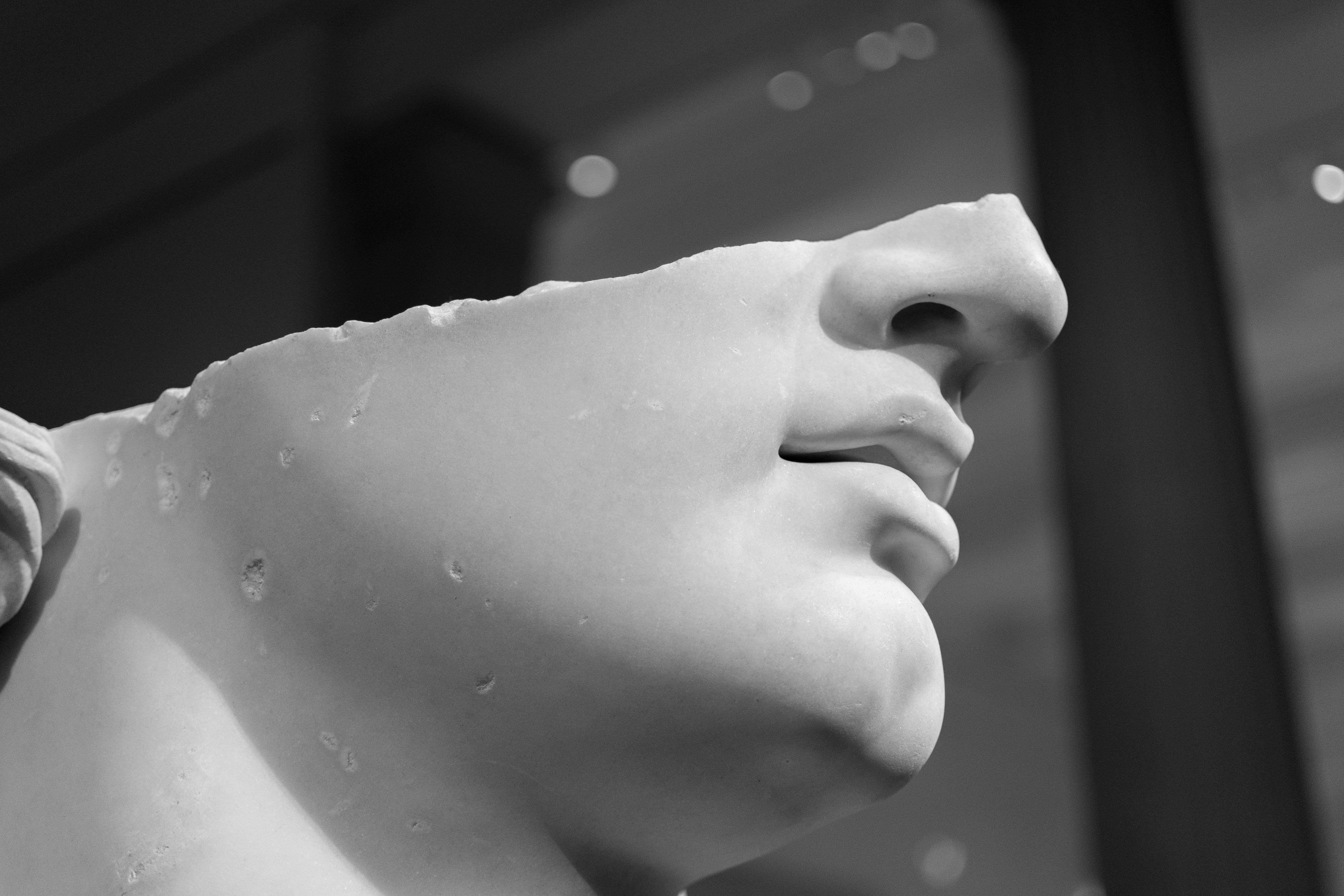 Een close-up van een wit marmeren beeld, gefotografeerd van onderaf. Alleen de neus, mond, kin en een deel van de hals zijn zichtbaar; het bovenste deel van het gezicht ontbreekt, waardoor de aandacht vooral naar de neus gaat.