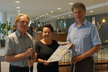 Portefeuillehouder Sharon Dijksma (Vervoerregio) reikt het eerste exemplaar van de voelbare plattegrond Noord/Zuidlijn uit aan twee vertegenwoordigers van de doelgroep blinde/slechtziende reizigers.