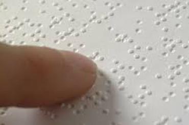 Een vinger leest een braillepagina