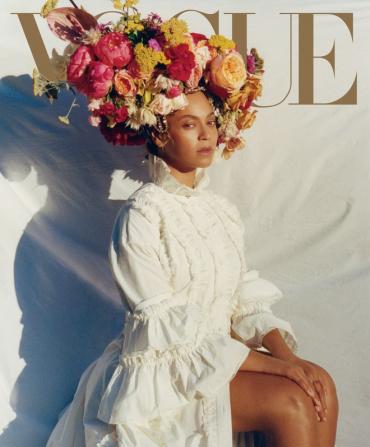 Cover Vogue met daarop Beyoncé, in een witte jurk van degelijke dikke stof en met een enorme kroon van bloemen op haar hoofd. 