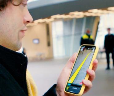 Man met een smartphone in zijn hand waarop een virtuele geleidelijn te zien is