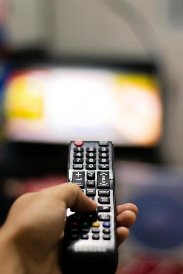 Hand die een afstandsbediening op een televisie richt