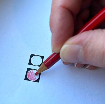 Vingers die een rood potlood vasthouden en een vakje inkleuren