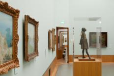 Eén van de zalen van museum Boijmans van Beuningen met links schilderijen en op de voorgrond een sculptuur.