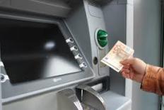 een hand die een briefje van 50 euro uit een geldautomaat haalt