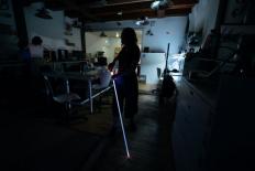 Een donkere ruimte waarin Debby Marchena met haar lichtgevende taststok te zien is. 