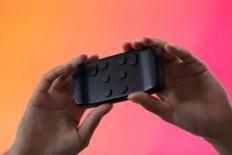 Twee handen houden een brailletoetsenbord ter grootte van een telefoon vast. 