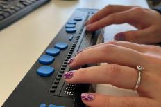 twee handen op een braille toetsenbord
