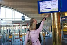 Twee mensen wijzen naar een informatiebord op een station